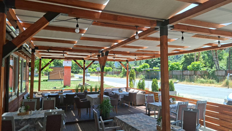 Outdoor dining area with wooden pergola and tables under a clear sky